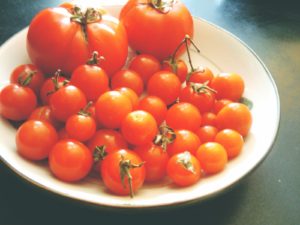 a large flatish white bowl with two regular size tomatoes and several small tomatoes