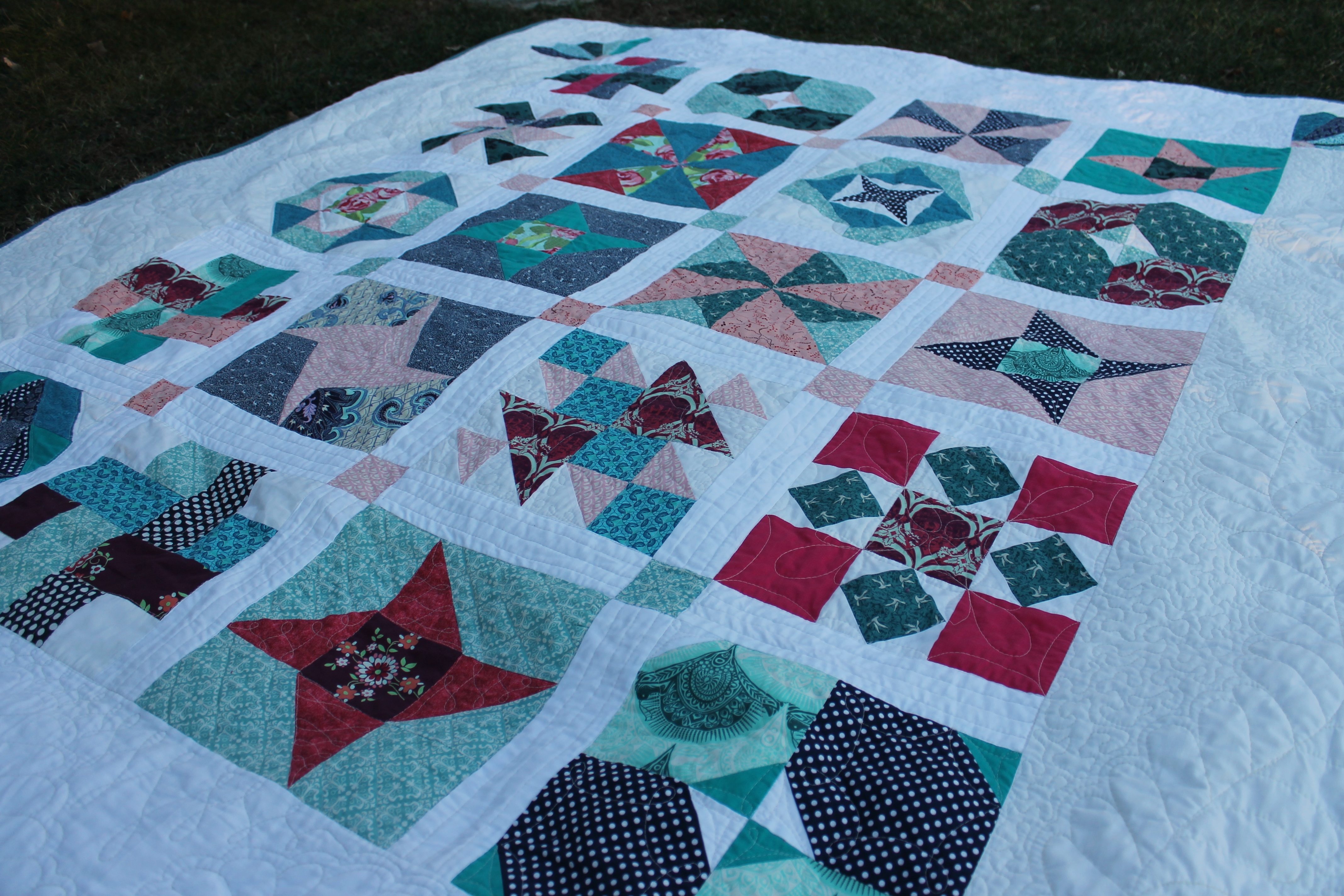 A Water Penny Sampler Quilt with turquoise and red variety of small squares on a white background