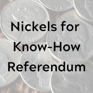 nickels in a pile on a wood table