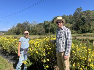 A young man and woman standing in a field of bright yellow flowers